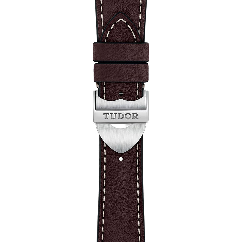 Close-up of a brown leather strap with white stitching, featuring a silver clasp engraved with TUDOR—a refined detail from the contemporary TUDOR 1926 watch collection.