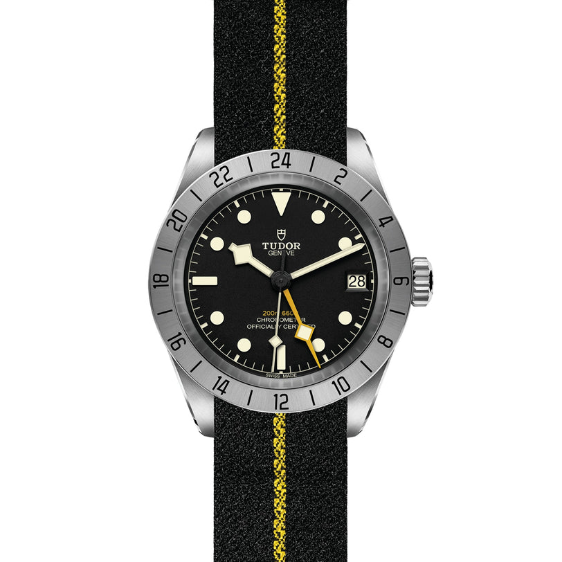 The TUDOR Black Bay Pro is a neo-vintage wristwatch with a black dial, yellow accents, date display, and a black fabric strap with a bold yellow stripe—an eye-catching tribute to the Black Bay diving style.