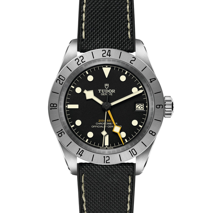The TUDOR Black Bay Pro features a black dial, luminescent markers, 24-hour bezel, date at 3 o’clock, and a black fabric strap with white stitching—capturing the neo-vintage spirit of classic Black Bay divers’ watches.