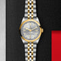 The TUDOR Black Bay One 36 S&G features a silver and gold two-tone bracelet, silver dial, gold bezel, and markers, shown on a textured black background.