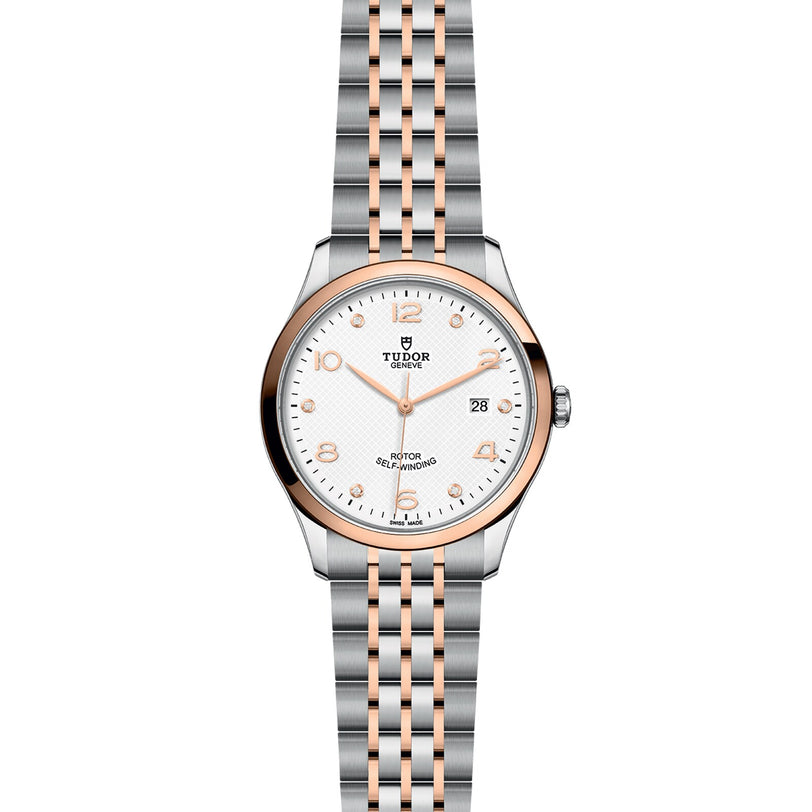 The TUDOR 1926 is a wristwatch with a silver and rose gold bracelet, white dial, gold hour markers, and a date display at 3 o’clock—an elegant tribute to classic mechanical watches.