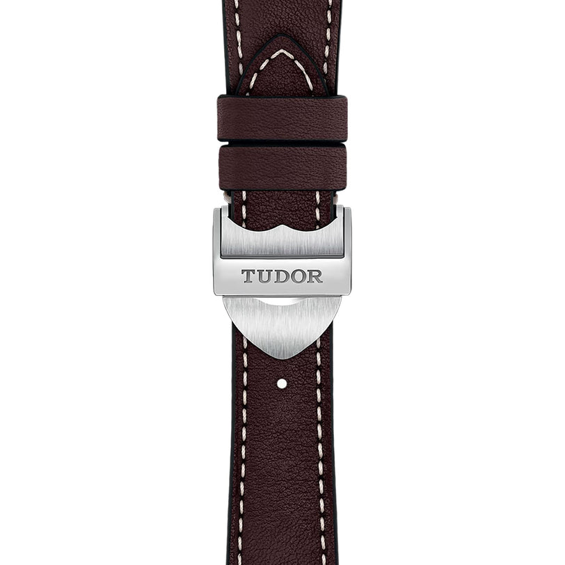 Close-up of a dark brown leather strap with white stitching and a silver clasp engraved TUDOR, highlighting the craftsmanship of the TUDOR 1926 timepiece.