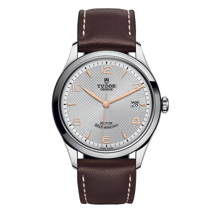 The TUDOR 1926 watch features a silver textured dial, rose gold numerals and hands, date window at 3 o’clock, and a classic brown leather strap—a standout in contemporary mechanical wristwatches.