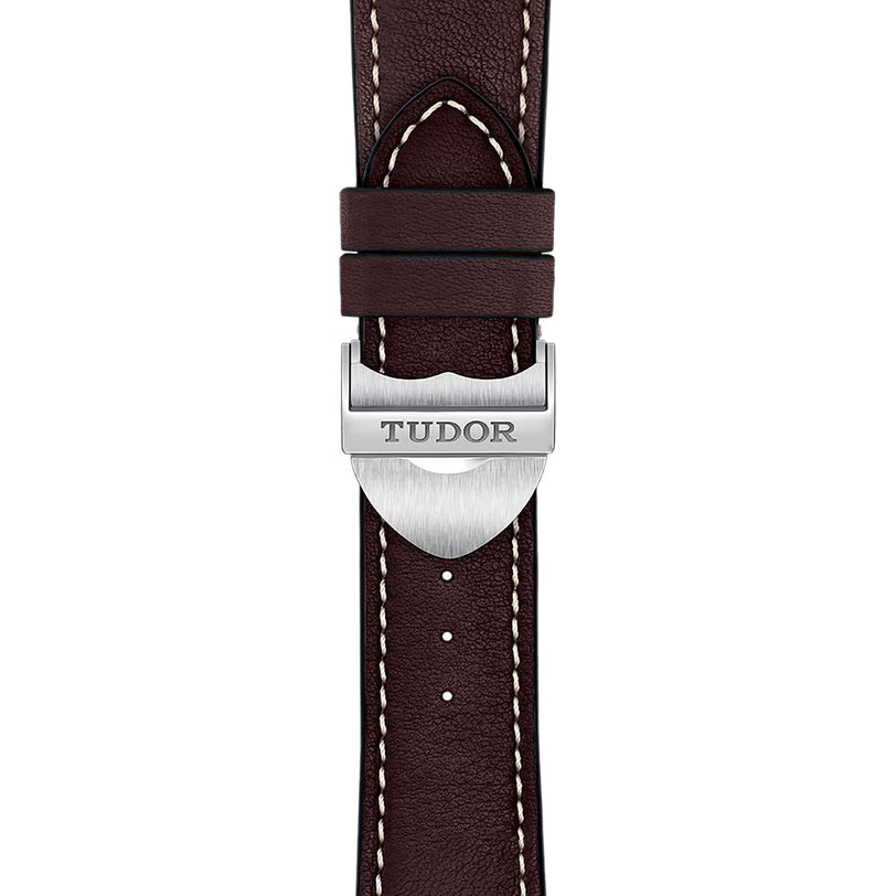 Close-up of a brown leather strap with white stitching and a silver buckle engraved with TUDOR, highlighting the classic design of the TUDOR 1926 watch.