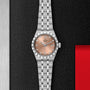 A TUDOR Royal wristwatch with a stainless steel case, salmon dial, Roman numerals, and diamond hour markers sits on a textured black surface, showcasing its sport chic style and automatic movement.
