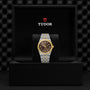 The TUDOR Royal wristwatch, featuring a gold bezel and black dial with automatic movement, comes in a sleek black TUDOR box—making a bold sport-chic statement.