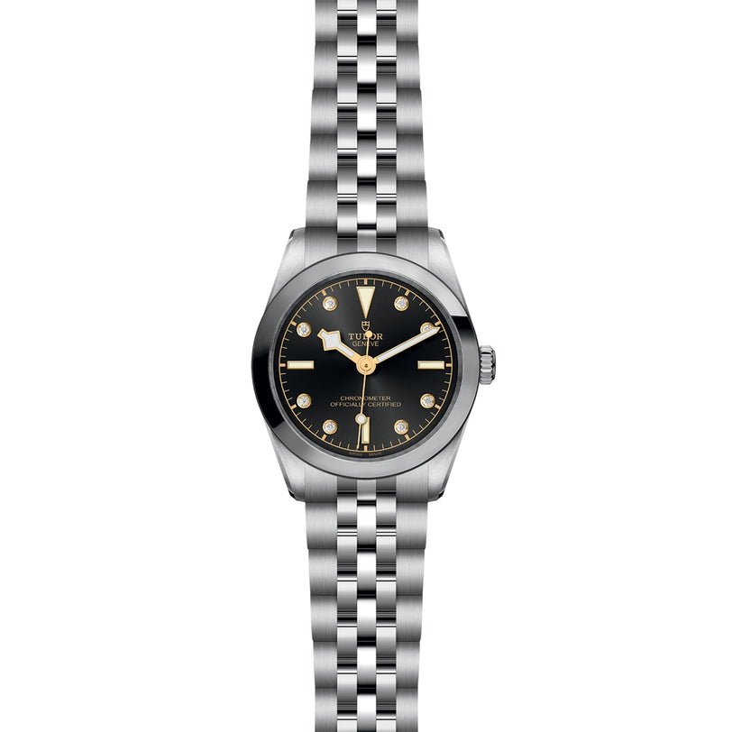A TUDOR Black Bay 31 wristwatch, featuring a black dial, gold hour markers, and a five-link silver metal bracelet, is displayed against a white background—highlighting the unisex chic style of this model.
