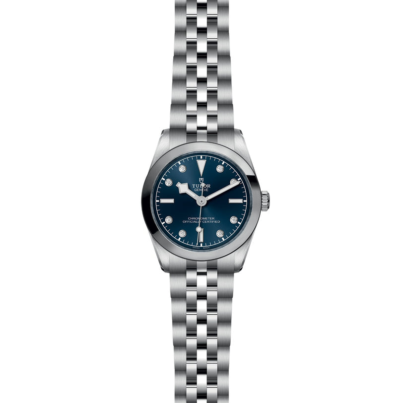 The TUDOR Black Bay One 31 is a stainless steel unisex wristwatch with a blue dial, silver hour markers, and a five-link bracelet, delivering chic style against a white background.