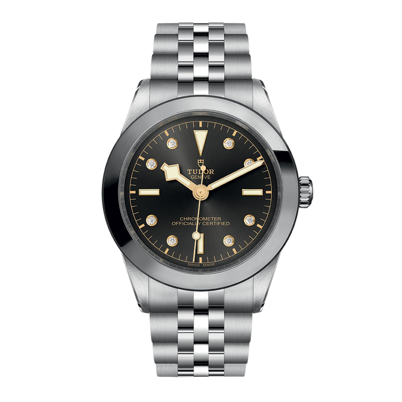 The TUDOR Black Bay One 39 is a unisex stainless steel wristwatch featuring a black dial, gold hour markers, silver bracelet, and date window at 3 o’clock.