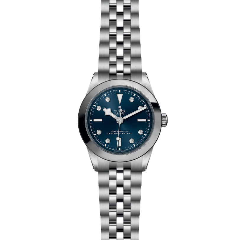 The TUDOR Black Bay One 39 is a unisex silver wristwatch with a blue dial, silver hour markers, and a metal link bracelet, inspired by Black Bay models and displayed on a white background.