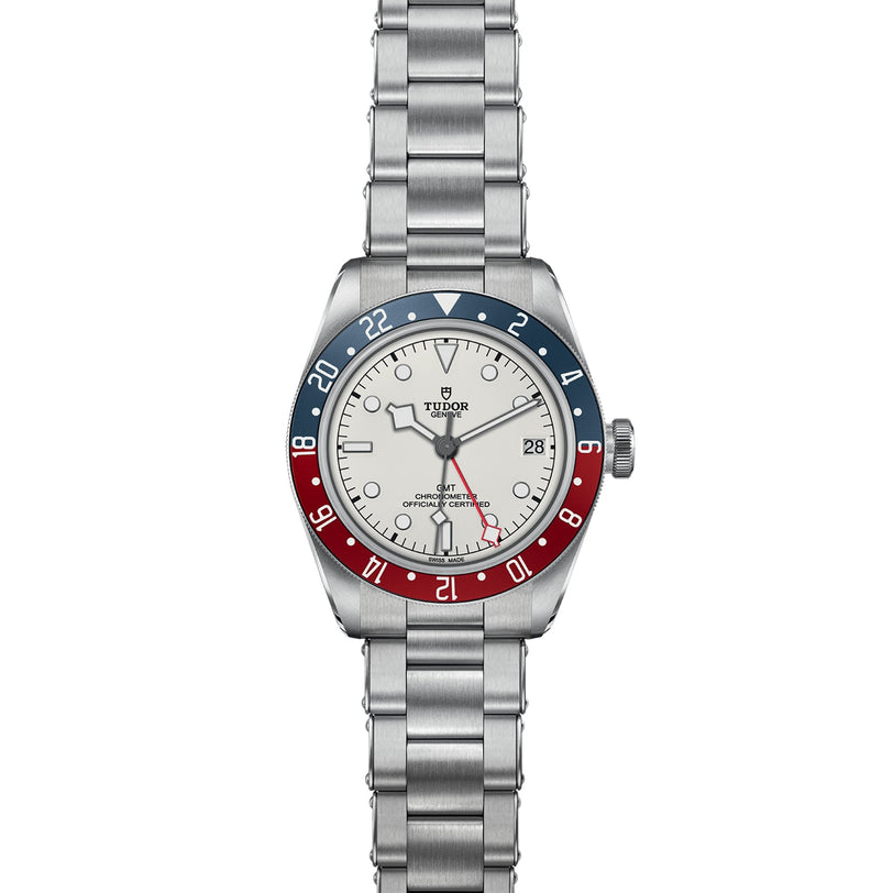 The TUDOR Black Bay GMT wristwatch features a stainless steel case, red and blue bezel, opaline dial, date display, and metal bracelet, shown from above.