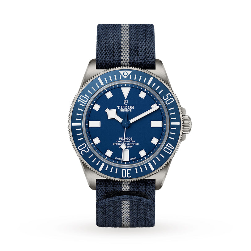 A TUDOR Pelagos FXD dive watch with a blue dial, striped fabric strap, silver bezel, and white markers is displayed on a plain white background—an outstanding modern diver’s timepiece.