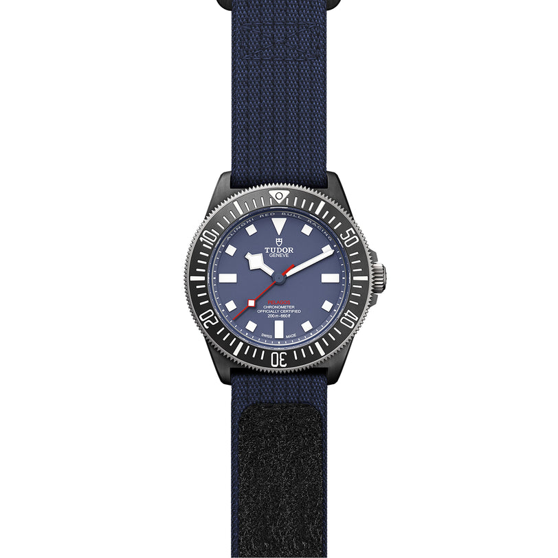 The TUDOR Pelagos FXD features a blue dial, white hour markers, black bezel, and blue fabric strap—designed for waterproof durability and precise underwater navigation.