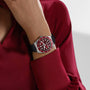 A person in a red shirt is wearing a TUDOR Black Bay 58 watch with a red face and black strap on their wrist.
