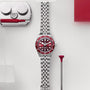 The TUDOR Black Bay 58 wristwatch with a red bezel and dial is displayed next to watch repair tools on a white background.