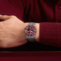 A person wearing a TUDOR Black Bay 58 wristwatch with a red dial, paired with a matching red sweater.