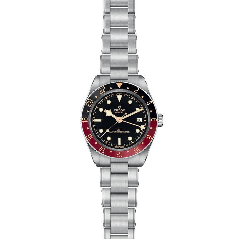 The TUDOR Black Bay 58 GMT dive watch features a stainless steel case, black dial, date at 3 o’clock, black and red bezel, and a metal link bracelet.