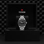 A TUDOR Black Bay wristwatch with a black dial and silver bracelet is showcased upright in an open black TUDOR box, emphasizing the signature style of the TUDOR Black Bay collection.
