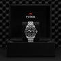 A TUDOR Black Bay stainless steel wristwatch with a black bezel and dial is presented in an open Tudor-branded box, highlighting the Black Bays signature diving watch design.