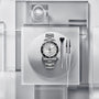 The TUDOR Black Bay 68 wristwatch displayed with tools arranged neatly on a frosted, geometric background.