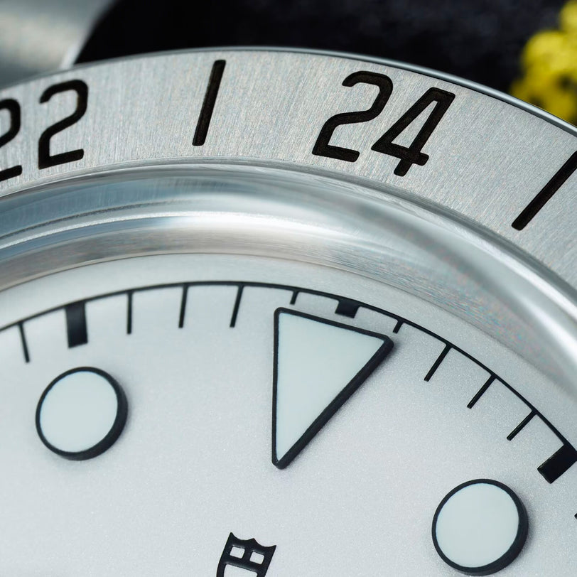 Close-up of the TUDOR Black Bay Pros silver bezel featuring numbers 22 and 24, with part of the white watch face and markers in view.