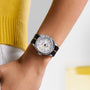 A person wearing a TUDOR Black Bay Pro silver wristwatch with a black and yellow strap and a yellow sweater.