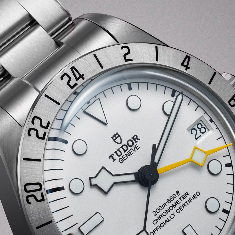 Close-up of the TUDOR Black Bay Pro, featuring a white dial, silver bezel, yellow-accented hand, and date display set to 28.