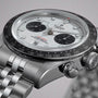 Close-up of a TUDOR Black Bay Chrono watch featuring a white dial, black bezel, and silver metal bracelet.