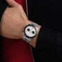 A person wearing a TUDOR Black Bay Chrono, a silver chronograph watch with a white dial and black subdials, on their left wrist.