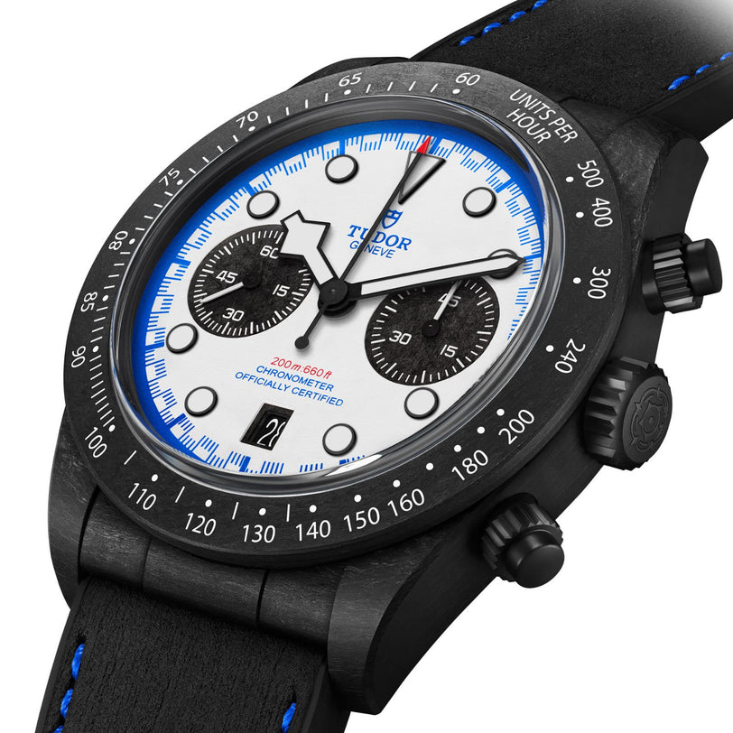 The TUDOR Black Bay Chrono features a white dial, black bezel, and a black leather strap with blue stitching.