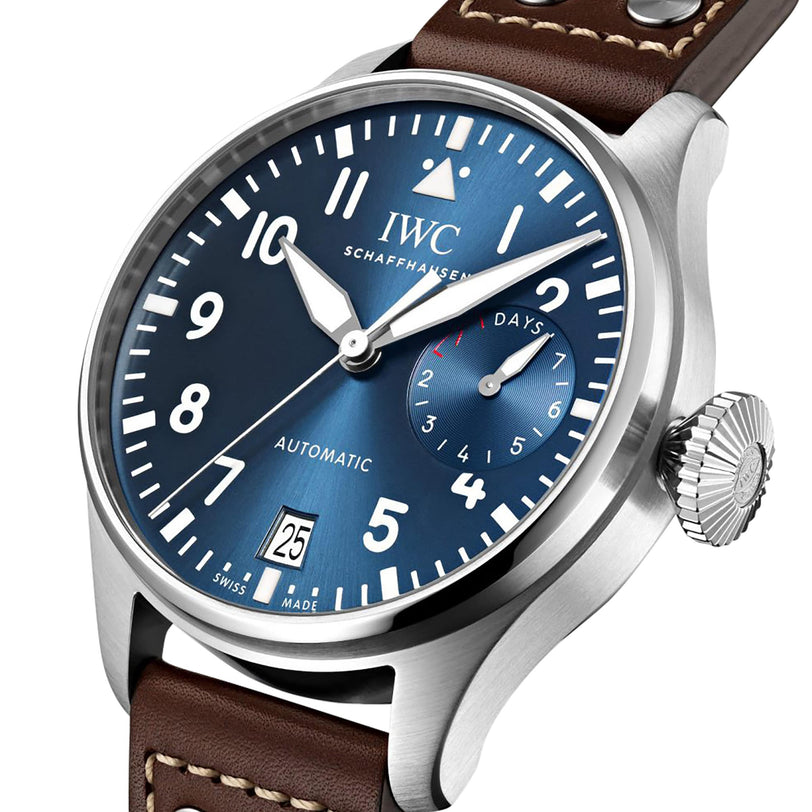 A close-up of the IWC Schaffhausen Big Pilots Watch Edition Le Petit Prince shows its automatic movement, blue dial, date window, power reserve indicator, stainless steel case, and brown leather strap.