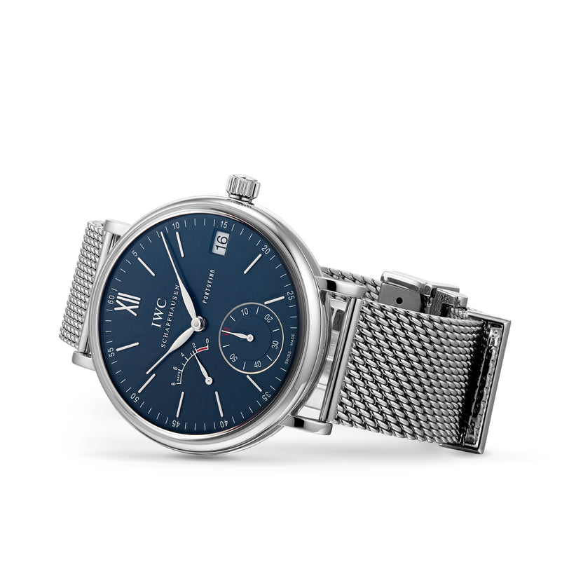 The IWC Schaffhausen Portofino Hand-Wound Eight Days features a silver-tone case, blue dial, mesh band, date window at 3 o’clock, subdial at 6 o’clock, and Roman numeral XII marker—a nod to classic Portofino style.