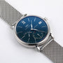 An IWC Schaffhausen Portofino Hand-Wound Eight Days watch with a blue dial, silver mesh band, Roman numeral at 12, and subdials for seconds and date, shown on a white background.