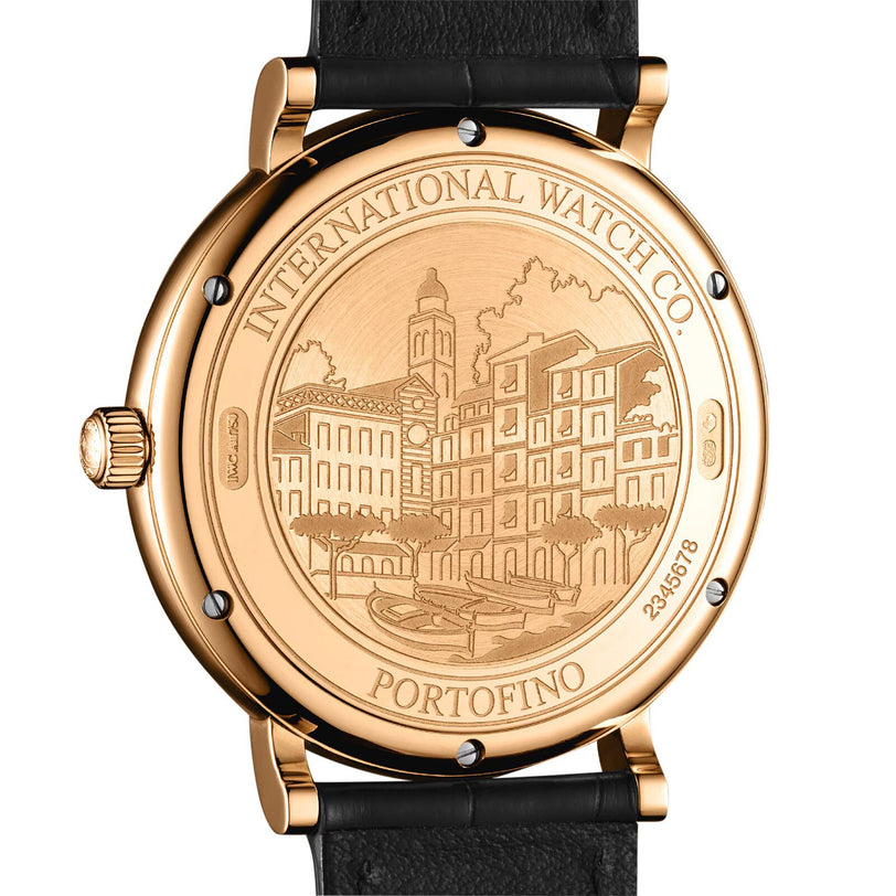 Close-up of a Portofino Automatic by IWC Schaffhausen, showing its gold case back engraved with a building scene and labeled International Watch Co. Portofino, with Swiss precision and a black leather strap.