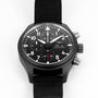 The IWC Schaffhausen Pilots Watch Chronograph Top Gun features a black case, black nylon strap, and displays time, day, and date on a white dial.