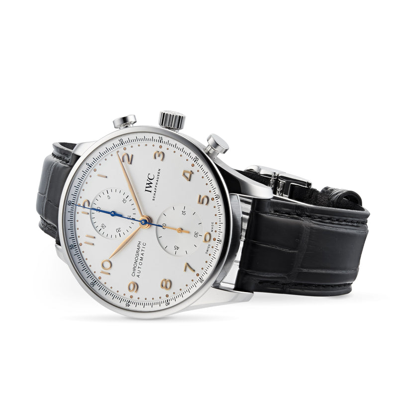 An IWC Schaffhausen Portugieser Chronograph wristwatch with a stainless steel case, white dial, black alligator leather strap, and blue and gold hands is shown resting on its side.