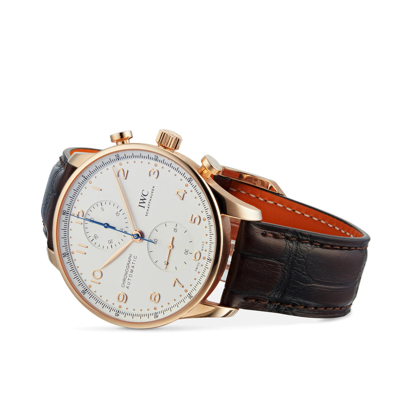 The IWC Schaffhausen Portugieser Chronograph showcases Swiss craftsmanship with its white dial, gold case, blue hands, brown leather strap, and side-angled chronograph subdials.