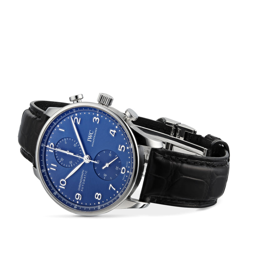 The IWC Schaffhausen Portugieser Chronograph, featuring a stainless steel case, blue dial with white numerals, two subdials, and a black leather strap, is displayed at an angle to highlight its refined automatic movement.