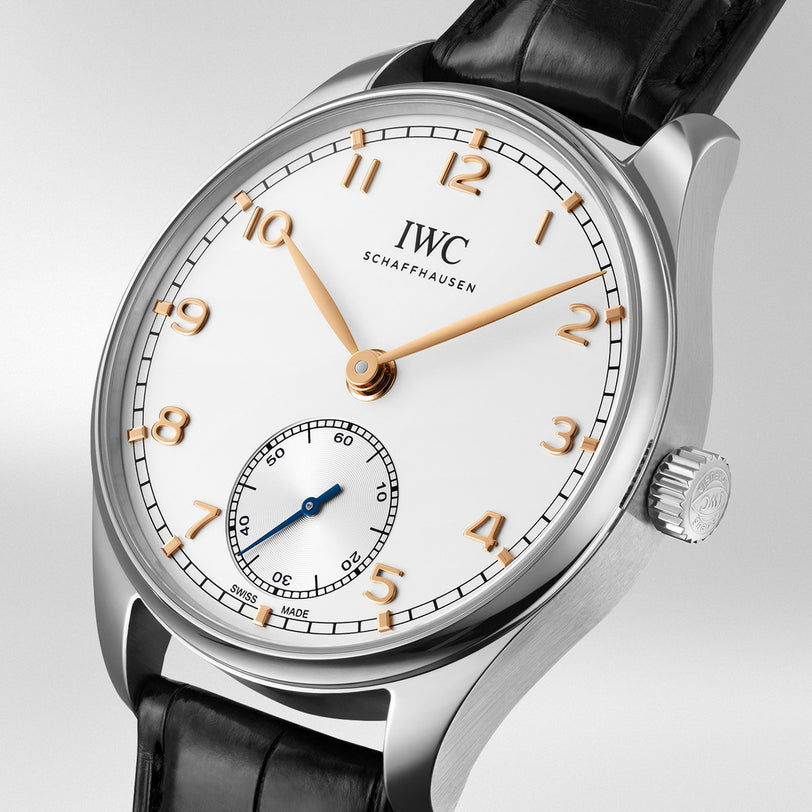 A silver IWC Schaffhausen Portugieser Automatic 40 wristwatch with a white dial, gold hour markers and hands, small seconds subdial at 6 o’clock, and black leather strap.