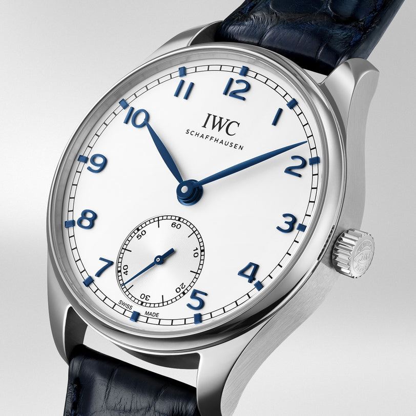 A close-up of an IWC Schaffhausen Portugieser Automatic 40 wristwatch featuring a white dial, blue hands, Arabic numerals, a sub-dial at 6 o’clock, and a black leather strap.