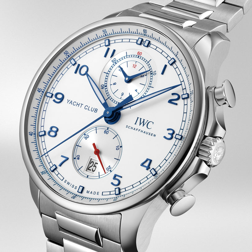 The IWC Schaffhausen Portugieser Yacht Club Chronograph features blue numerals and hands, two subdials, a date window at 3 o’clock, and a metal bracelet—showcasing refined nautical sports watch style on a light background.