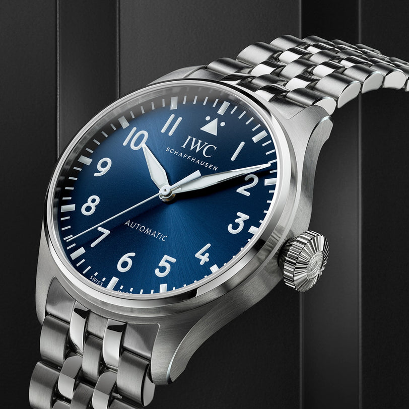 A close-up of the IWC Schaffhausen Big Pilots Watch 43 automatic, featuring a blue dial with white numerals and a stainless steel case and bracelet, set against a dark background.