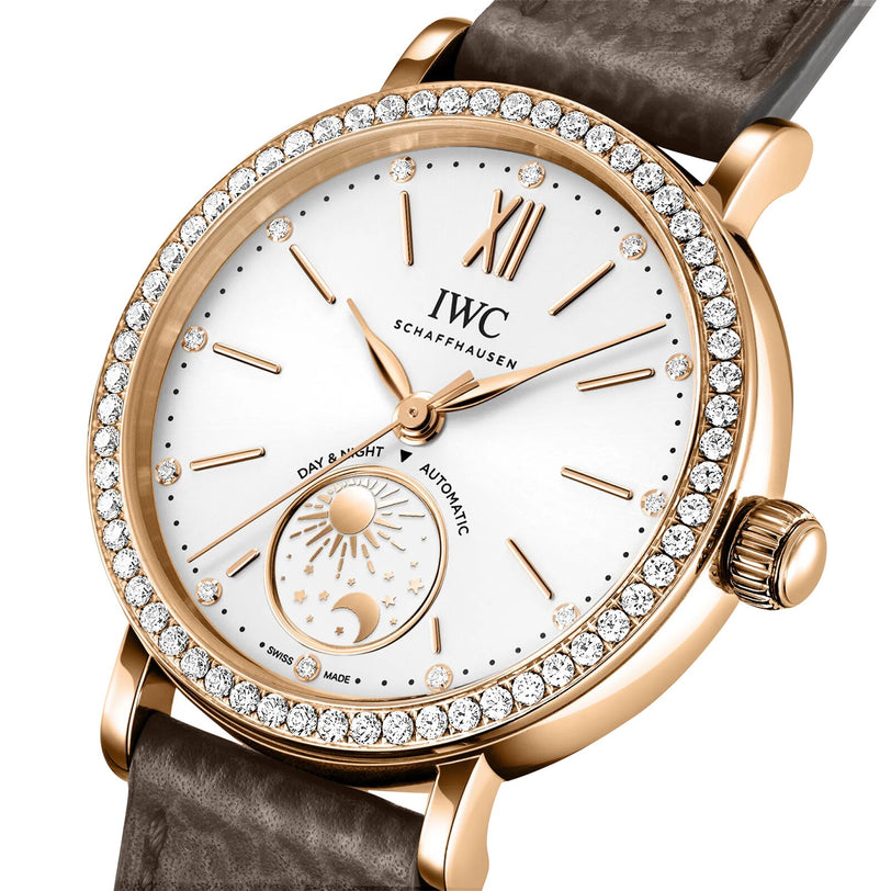 The IWC Schaffhausen Portofino Automatic Day & Night 34 features a white dial, day and night display, diamond-set bezel, and a brown leather strap for a luxurious look.