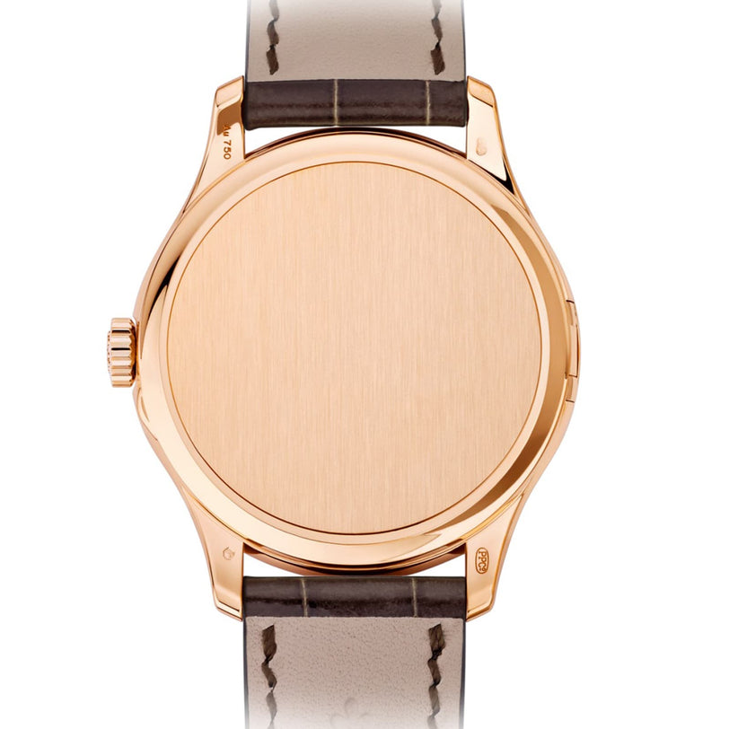 The Patek Philippe Calatrava 5227R-001 is a gold wristwatch with a blank face and a brown leather strap, viewed from above.