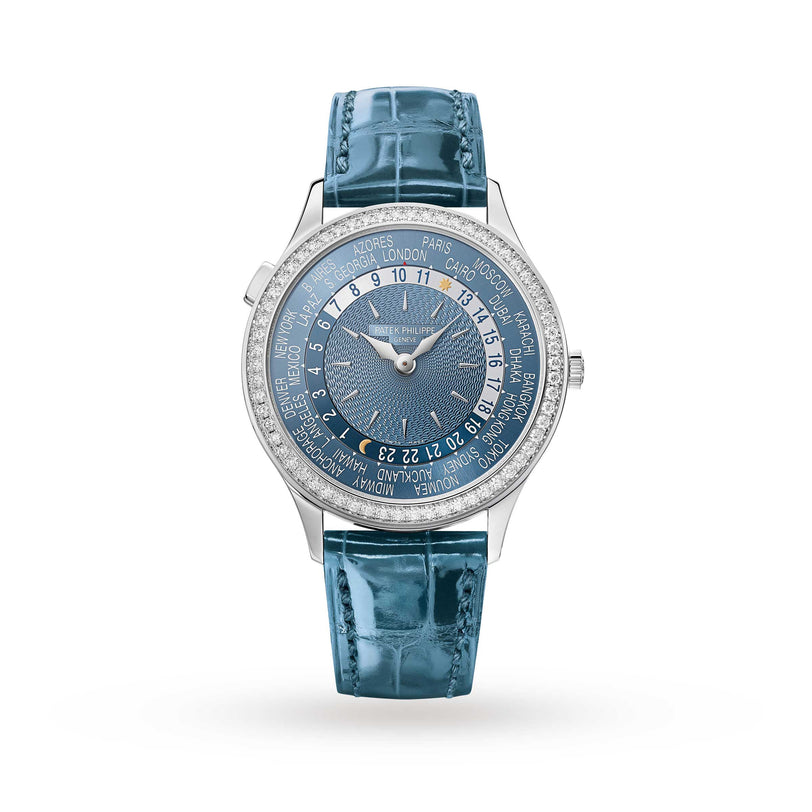 The Patek Philippe Complication 7130G-016 is a world time wristwatch featuring a blue leather strap, silver case, city names, and a textured blue dial.