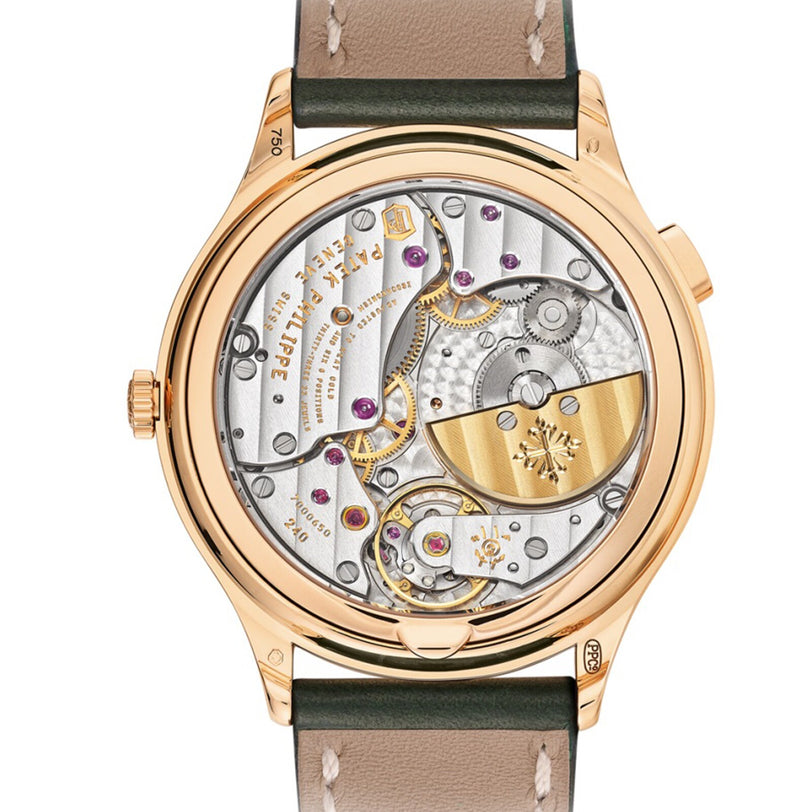 The Patek Philippe Complication 7130R-014 features a gold luxury case back revealing intricate mechanical movement and gears, complemented by an elegant leather strap.