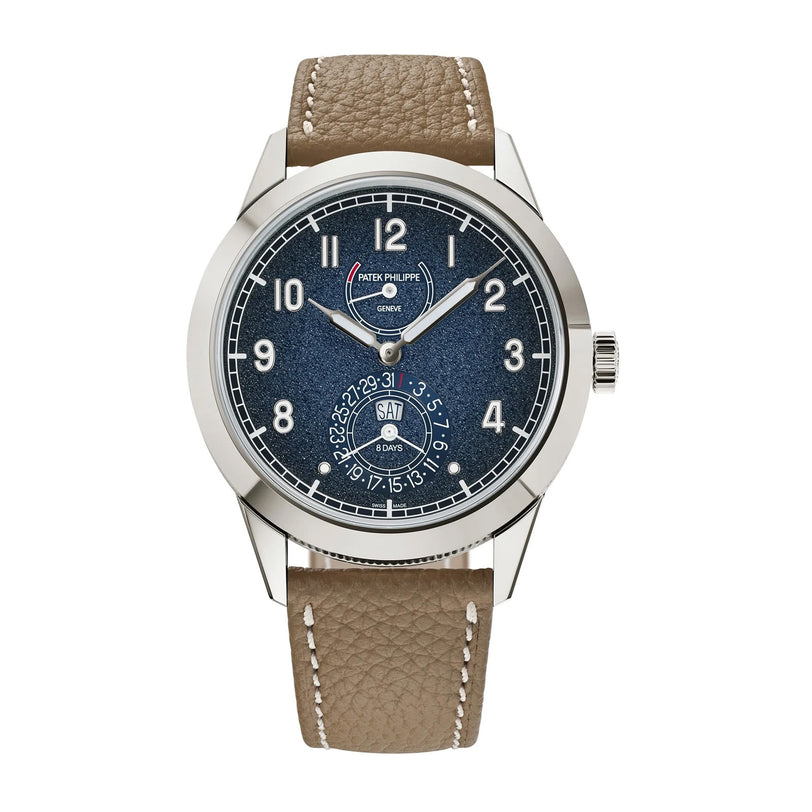 The Patek Philippe Complications 5328G-001 is a luxury wristwatch featuring a blue dial, white markers, and a brown leather strap.