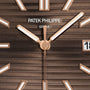 Close-up of the Patek Philippe Cubitus 7128/1R-001 watch face in brown with gold hands, white markers, and date display.