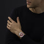 A man in a black sweater wears a Chopard Mille Miglia Classic Chronograph with a brown strap and red face on his left wrist.