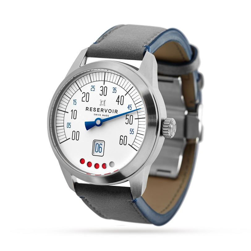 The Reservoir Tiefenmesser features a silver case, white dial, blue hand and numerals, date window at 6 o’clock, five red dots, and a dark leather strap—evoking classic submarine equipment in this unique timepiece.